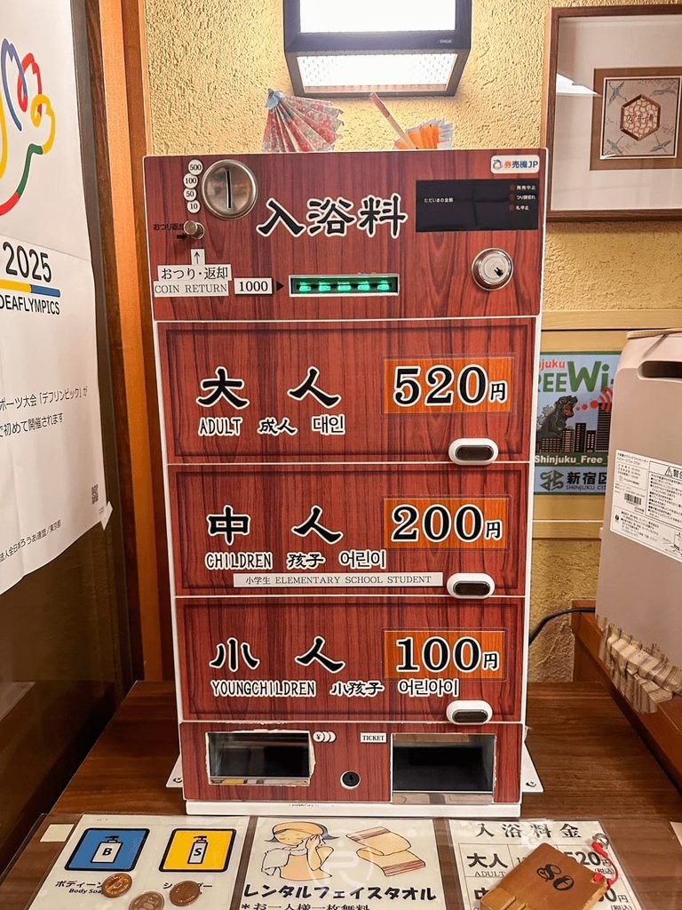 [自動售票機券売機]： 門口擺放的傳統自動購票機，標示大人 520 日圓入浴券按鈕。