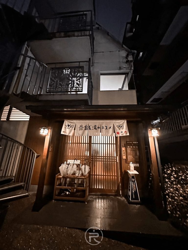 [正門夜間溫暖燈火]： 傳統日式木造門面在暖黃燈光映照下，展現靜謐的大正浪漫氛圍。
