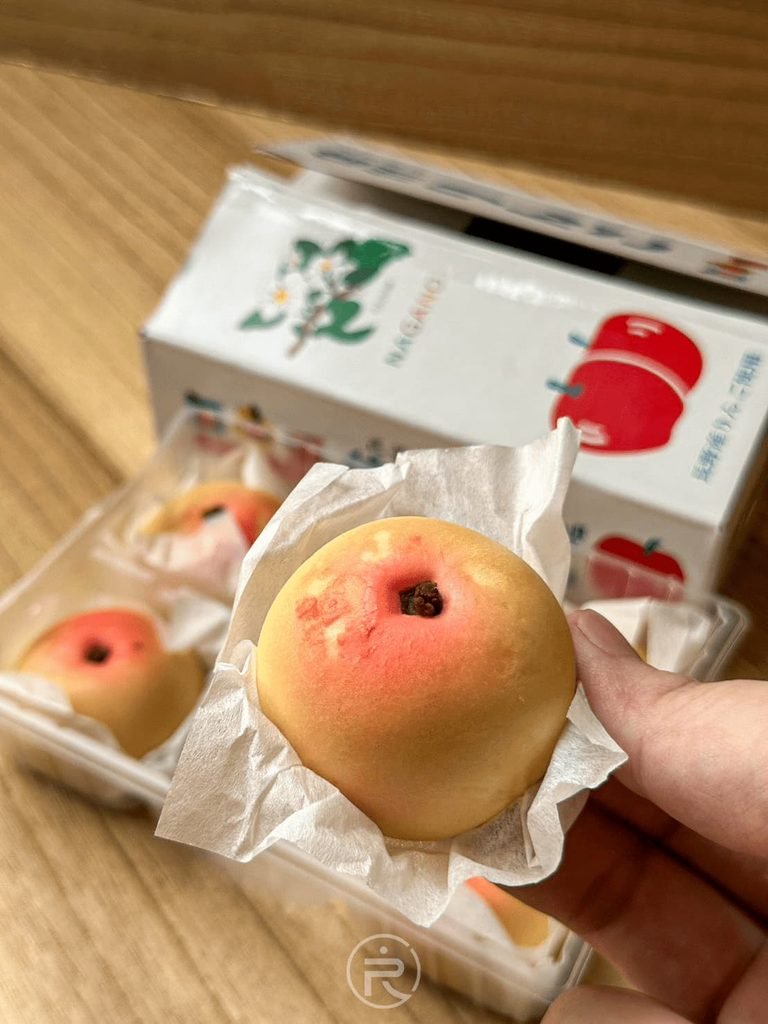  [手拿迷你小蘋果]： 手持一顆以白紙襯托的迷你小蘋果造型和菓子，表皮紅黃漸層做工逼真。