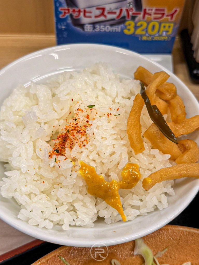 [越光米白飯佐漬物]： 熱騰騰白米飯撒上桌邊特製七味粉，搭配爽脆的黃金醃蘿蔔條（割干大根漬）。