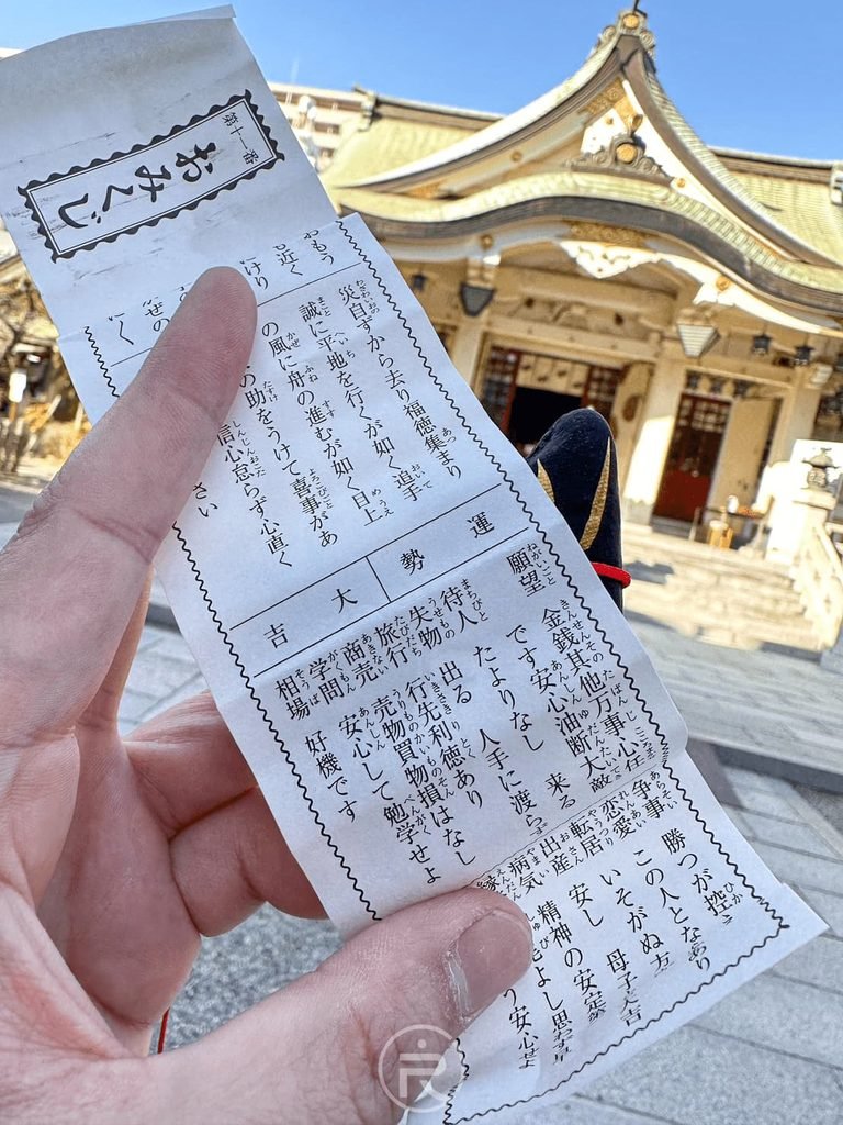  [展開吉籤詩]： 手持在難波八阪神社抽到的「吉」字神籤紙本，求得好運與指引。
