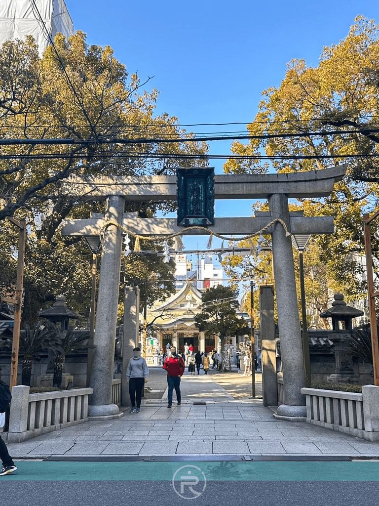 [大鳥居街道視角]： 從街角遠眺難波八阪神社正門鳥居，石板參道直通神聖境內。
