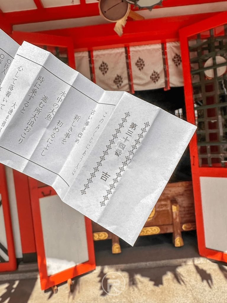  [手持神籤紙本]： 在玉造稻荷神社拜殿前展開抽到的日式神籤（おみくじ），祈求吉運順遂。