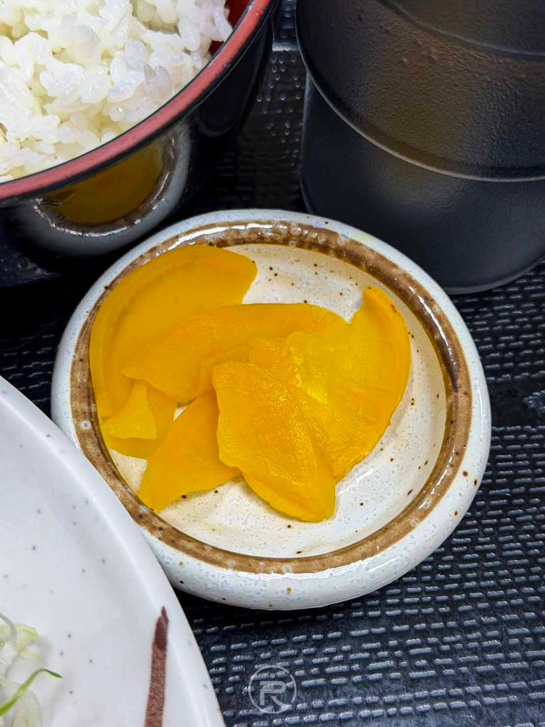 [黃金醃蘿蔔碟]： 日式定食經典小菜：爽脆微甜的金黃色澤醃蘿蔔（沢庵漬）。