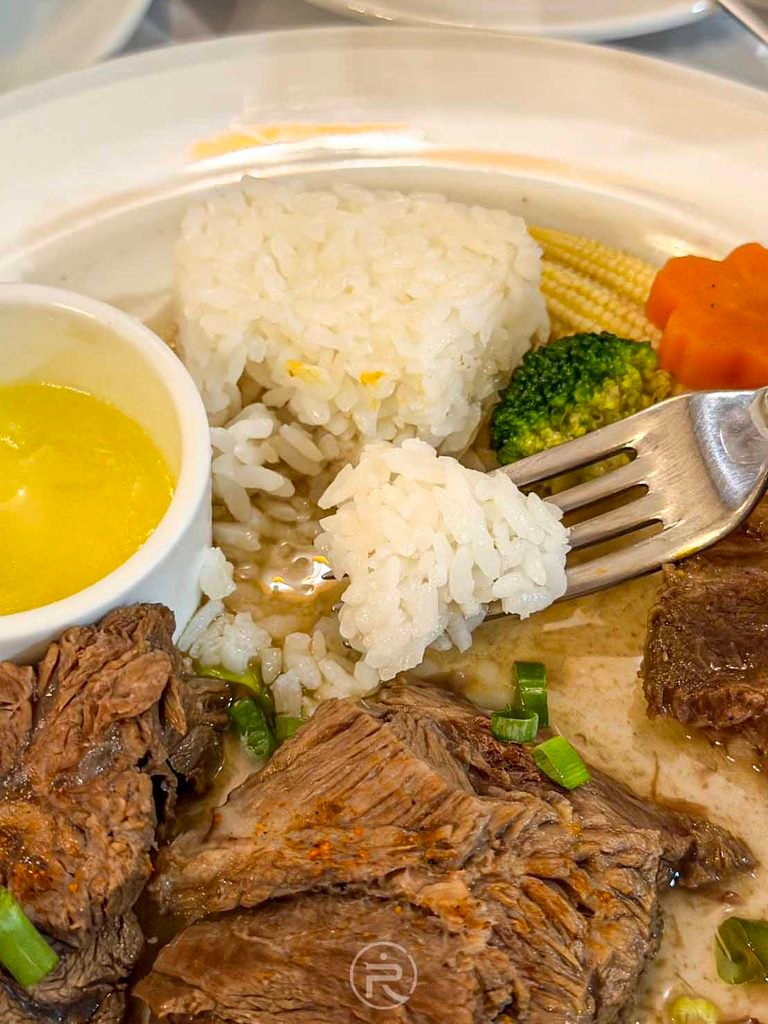  [叉子舀飯與牛肉]： 叉子同時舀起白飯與燉牛肉碎，吸收肉汁的白米飯格外鮮甜。
