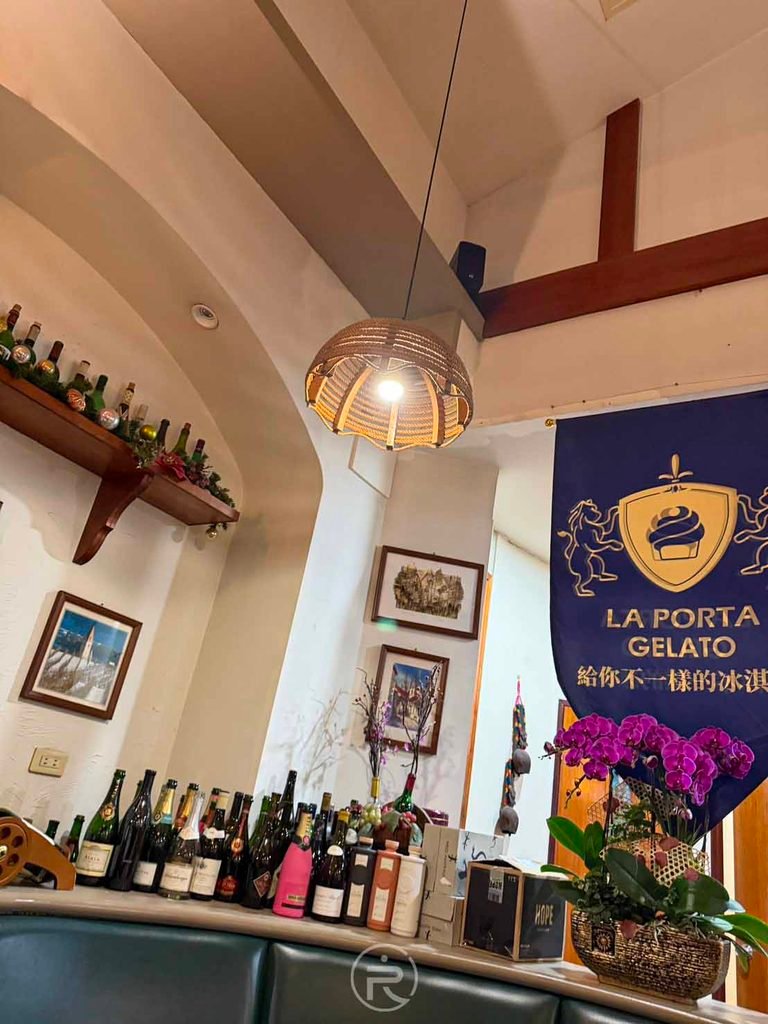  [義式冰淇淋掛布]： 店內陳列的歐洲紅酒瓶與進口義式冰淇淋（LA PORTA GELATO）標誌。