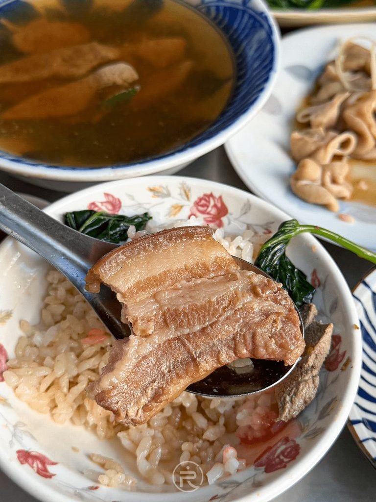 [湯匙舀起大塊爌肉]： 湯匙舀起厚切三層肉爌肉，肥瘦相間且滷得軟嫩透亮。
