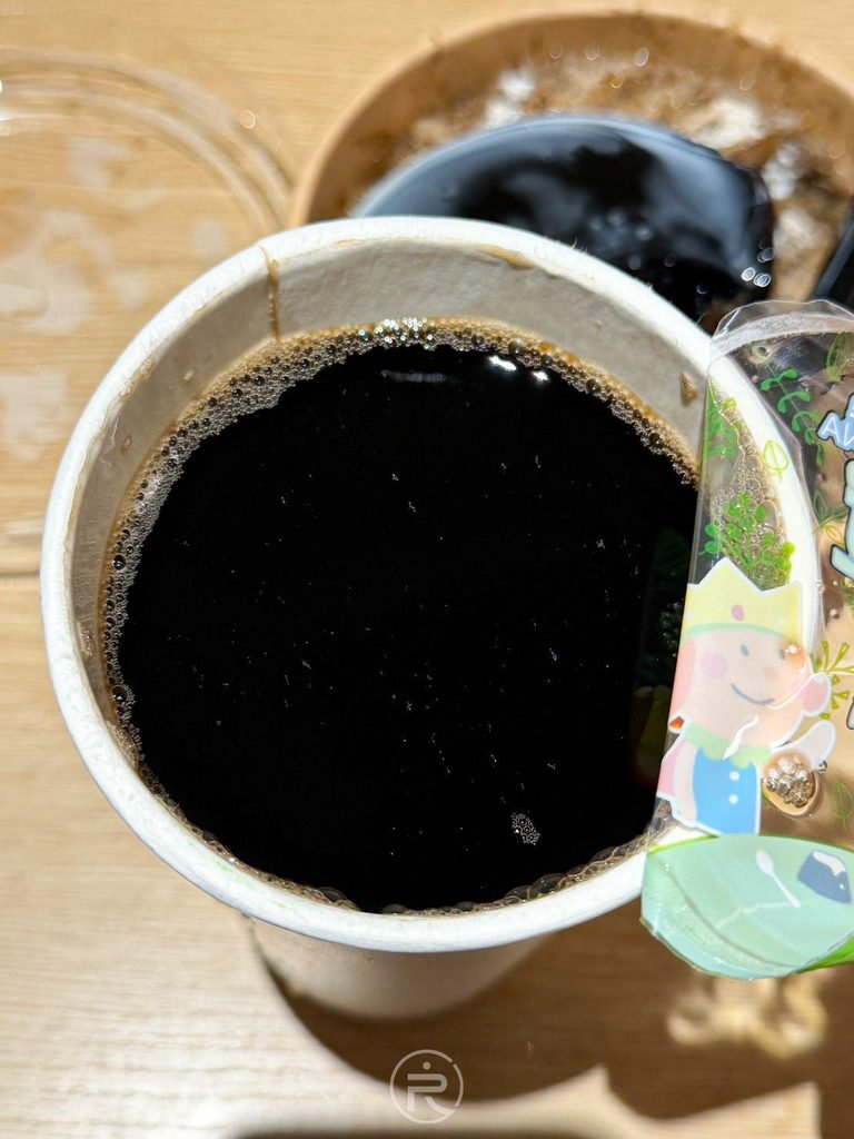  [紙杯仙草茶俯拍]： 撕開封膜俯瞰深黑色澤的冰涼原味仙草茶，散發天然青草清香。