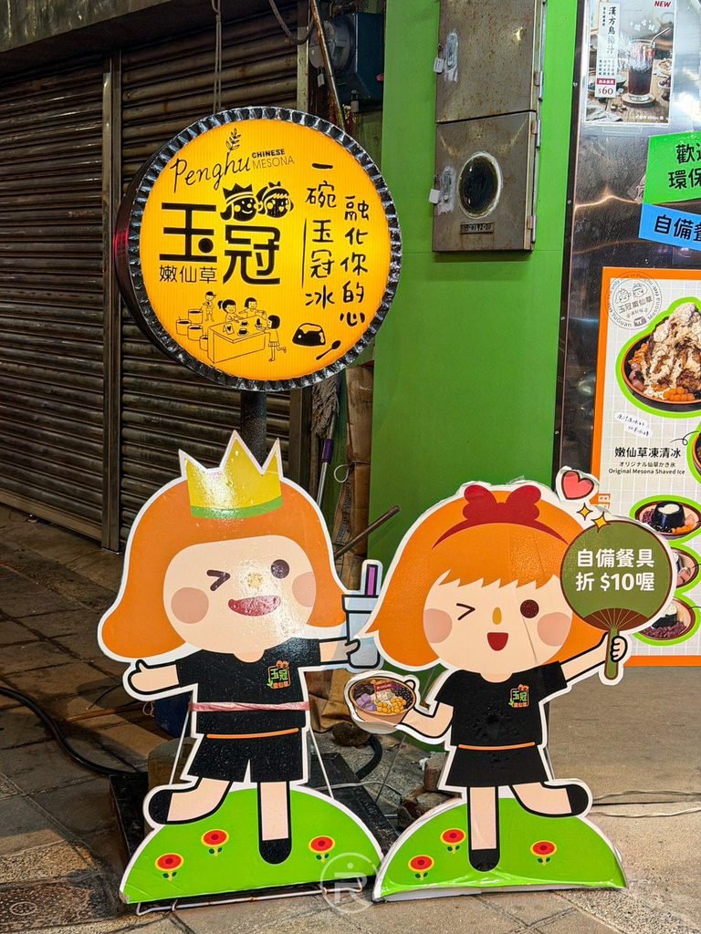  [門口可愛公仔立牌]： 玉冠嫩仙草門口擺設的代表性黃色圓形招牌與雙人可愛公仔立牌。