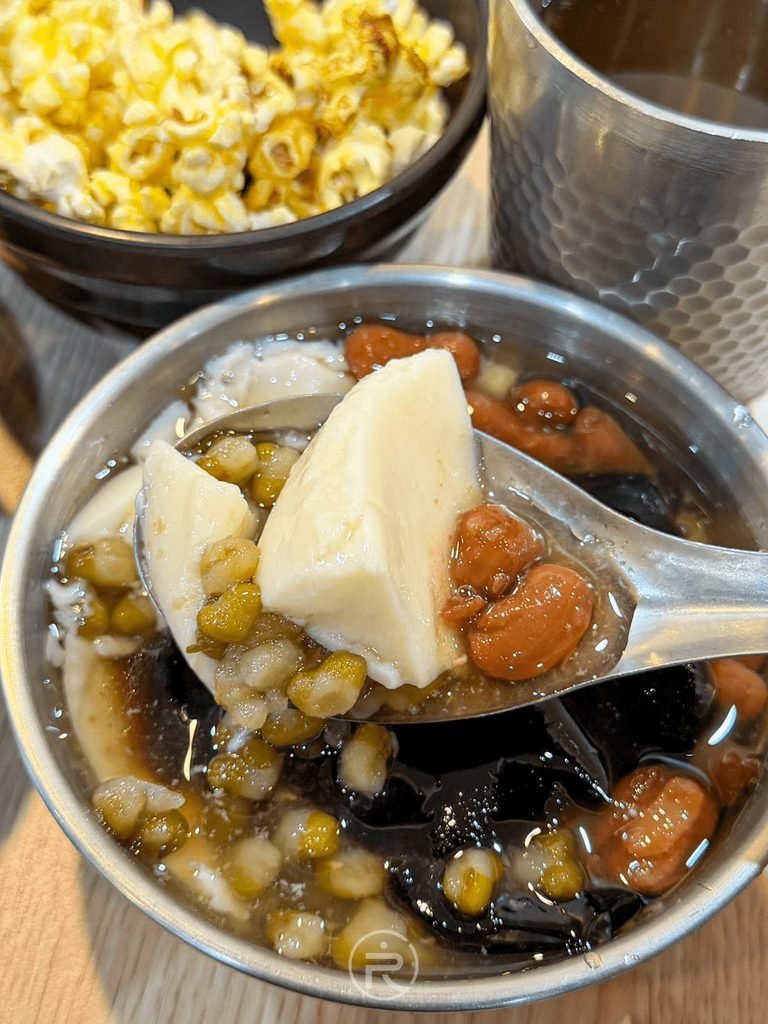  [湯匙舀古早味豆花]： 舀起綿密白嫩的手工豆花塊，散發自然黃豆香。