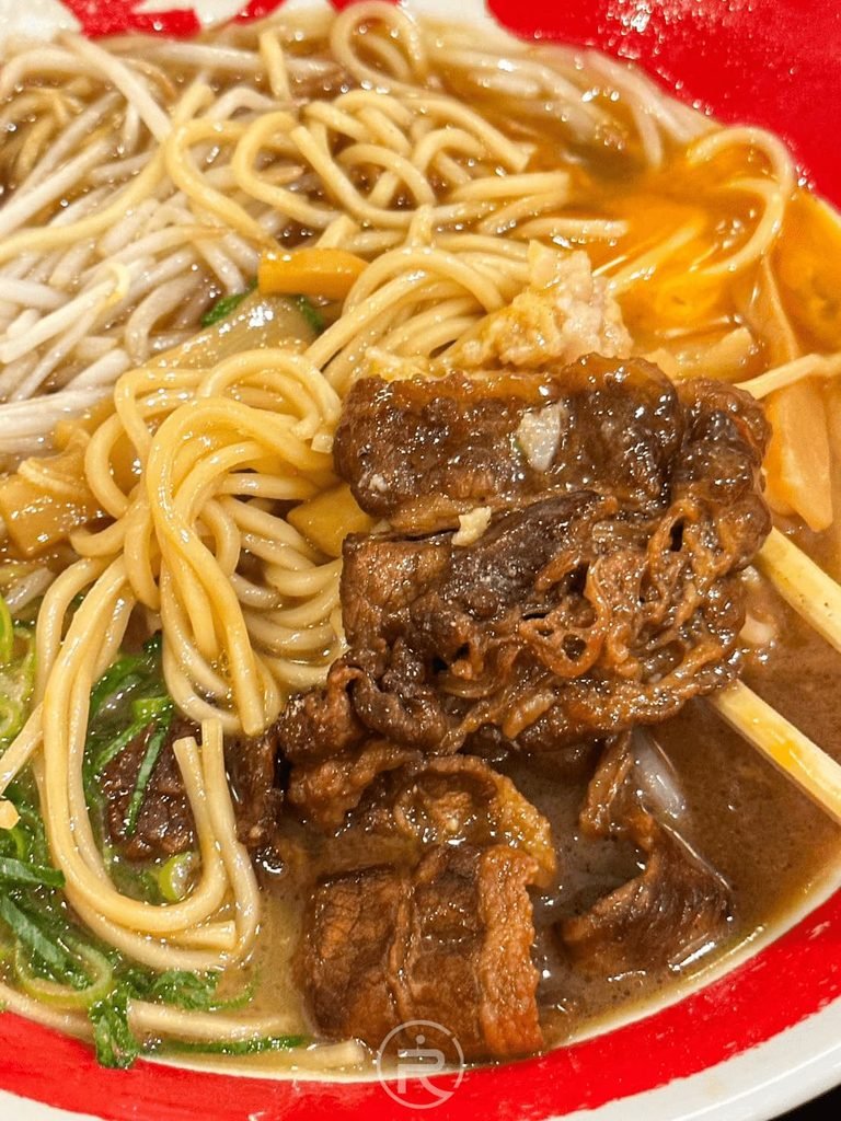 [拉麵配料特寫]： 德島拉麵東大特寫，吸附濃郁甘辛醬油湯頭的中細麵條與壽喜燒五花肉。