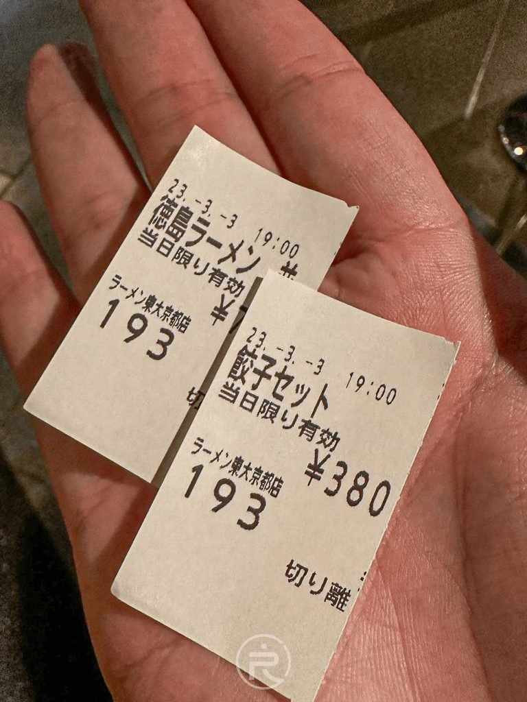  [紙本餐券明細]： 手持東大拉麵與餃子套餐（380日圓）的實體取餐明細券。