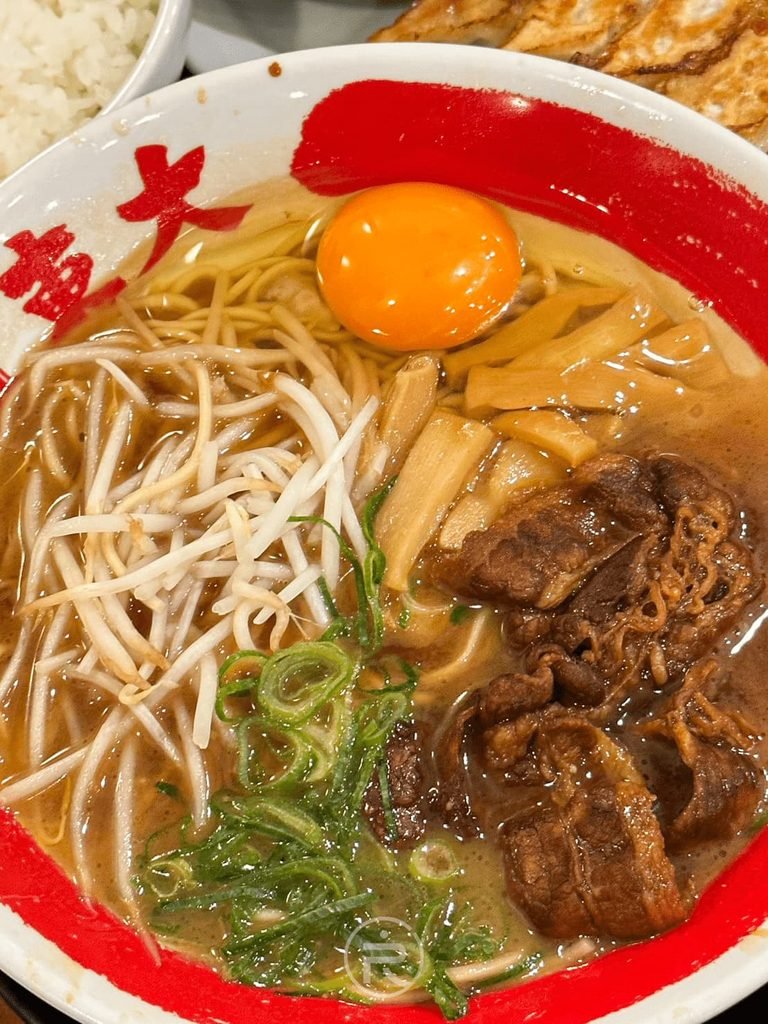[打入生蛋黃全貌]： 德島拉麵碗正中央打入整顆新鮮生蛋黃，濃稠黑系湯頭色澤誘人。