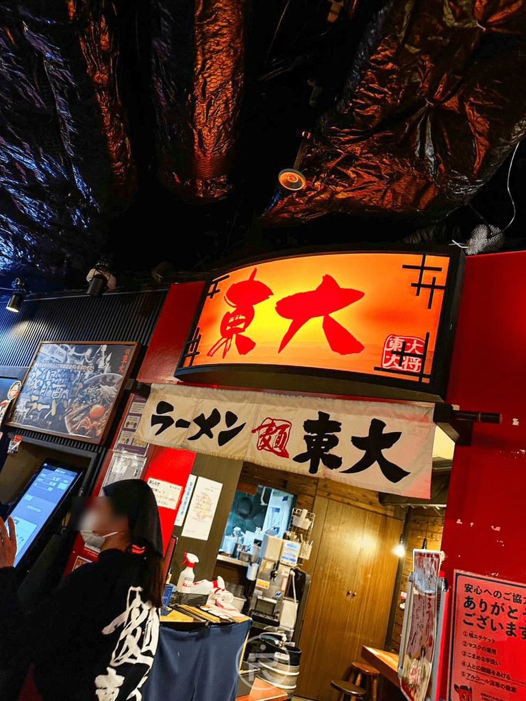 [拉麵小路店面入口]： 位於京都拉麵小路內的「ラーメン東大」熱鬧店門口與紅色招牌。